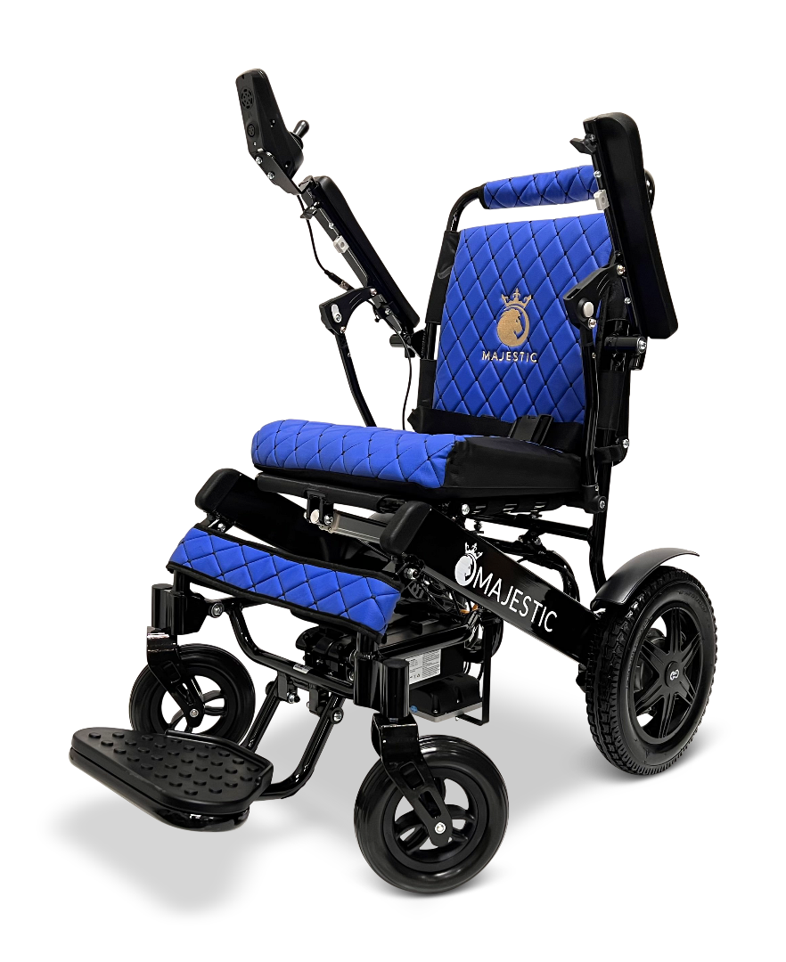 The ComfyGo MAJESTIC IQ-9000 Auto Reclining Electric Wheelchair features black and blue quilted upholstery, large rear wheels, adjustable armrests, a footrest, and a digital joystick controller. The Majestic logo is displayed on the seat and frame.